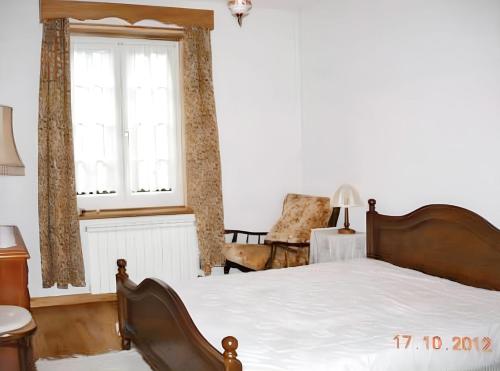 a bedroom with a bed and a window and a chair at Comfortable house with mountain view and shared pool in Pedraça