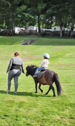 a woman is leading a child on a horse at Bungalow charmant à Rochechouart avec vue sur lac in Rochechouart
