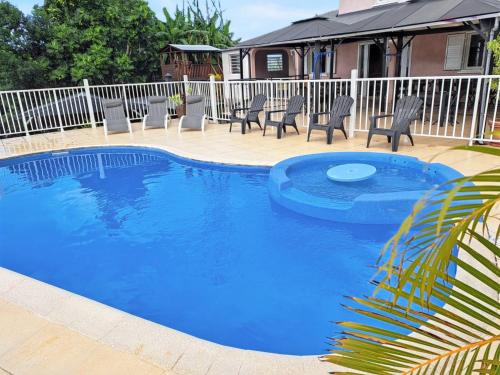 a blue swimming pool with chairs and a fence at Villa enchanteresse à Saint-Benoît avec piscine privée in Saint-Benoît