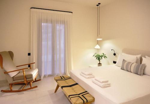 a bedroom with a bed and a chair and a window at Agave Donousa Suites in Donoussa