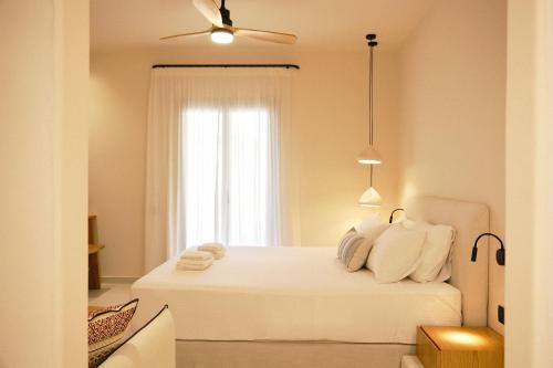 a bedroom with a white bed with a window at Agave Donousa Suites in Donoussa