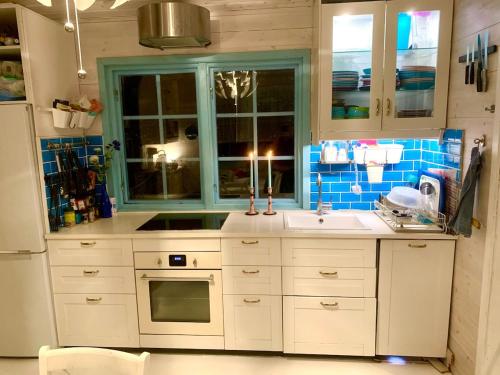 a kitchen with white cabinets and a sink and a window at Underbart litet hus i lantligt läge in Hemse
