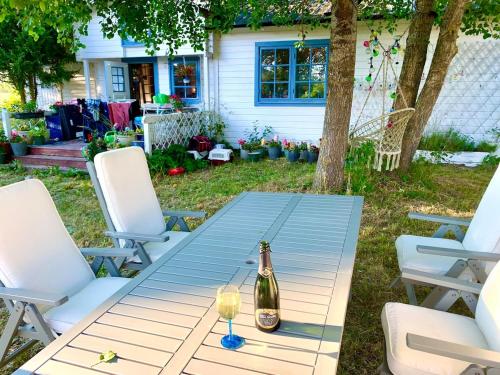a bottle of champagne sitting on a picnic table with two chairs at Underbart litet hus i lantligt läge in Hemse