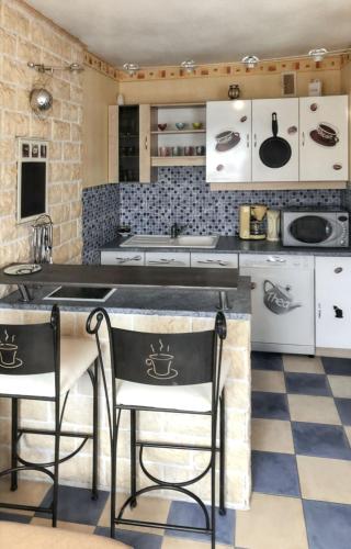 une cuisine avec des placards blancs et des tabourets noirs dans l'établissement Appartement confortable Metz 51m² + Parking, à Metz