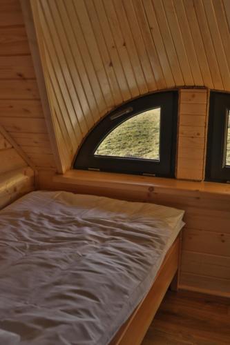 a bed in a cabin with a small window at Domki 15 szczytów in Zawoja