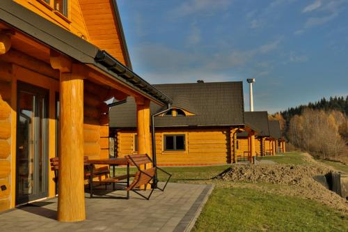 a wooden cabin with a table and chairs on a patio at Domki 15 szczytów in Zawoja