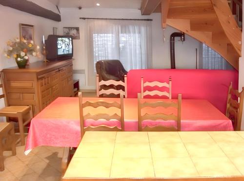 a dining room with a table and a pink bed at Maison chaleureuse près des pistes de Barcelonnette - Cheminée in Barcelonnette