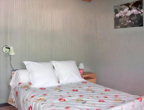 a bed with white sheets and red flowers on it at Maison chaleureuse près des pistes de Barcelonnette - Cheminée in Barcelonnette
