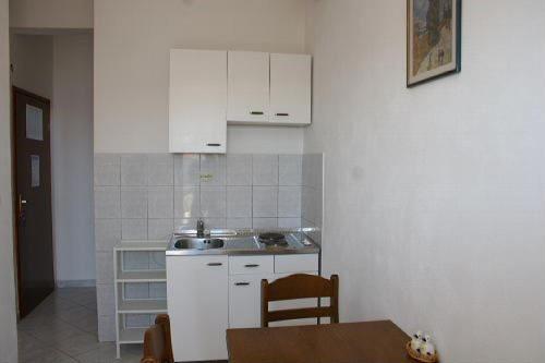 a kitchen with white cabinets and a table and a dining room at Apartments Gordana in Trogir