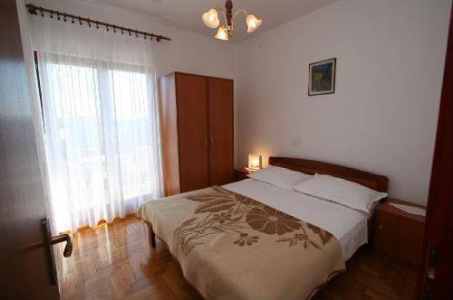 a bedroom with a bed and a large window at Apartments Gordana in Trogir