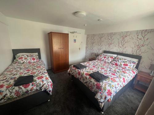 a bedroom with two beds and a wooden cabinet at The Holland arms hotel in Gaerwen