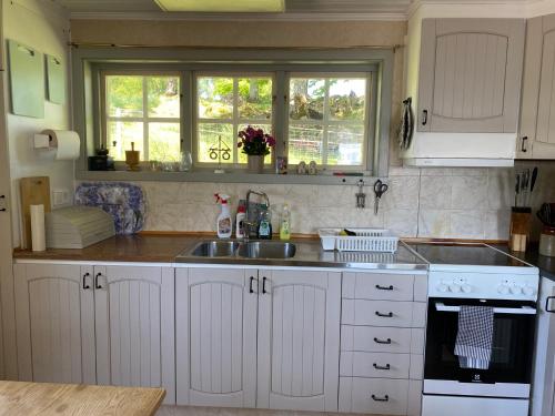 a kitchen with white cabinets and a sink at Joarsbo, Stuga 1, Sjölyckan in Kalv