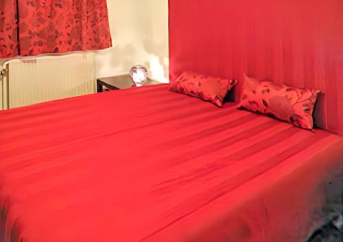 a red bed with red sheets and red pillows at Spacious house with garden in Comblain-au-Pont in Comblain-au-Pont