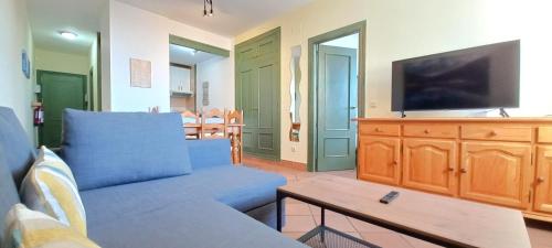 a living room with a blue couch and a tv at Plaza Andalucía Edificio Salvia in Monachil