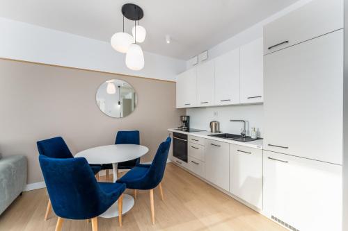 a kitchen with white cabinets and blue chairs and a table at FARO Apartamenty Polanki Aqua SPA Deluxe 4 baseny w cenie, Pools inklusive in Kołobrzeg