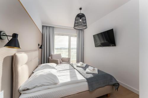 a bedroom with a bed and a tv and a chair at FARO Apartamenty Polanki Aqua SPA Deluxe 4 baseny w cenie, Pools inklusive in Kołobrzeg