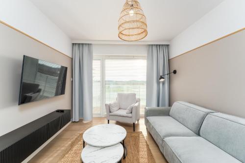 a living room with a couch and a chair at FARO Apartamenty Polanki Aqua SPA Deluxe 4 baseny w cenie, Pools inklusive in Kołobrzeg