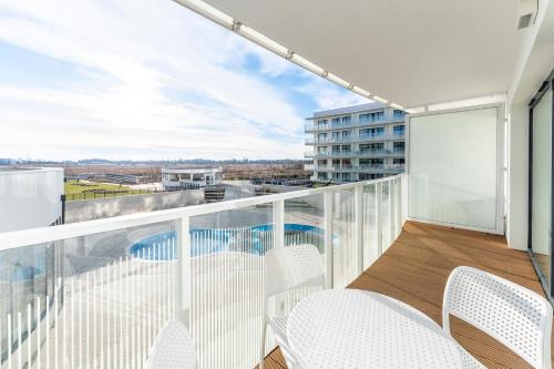 a balcony with white chairs and a swimming pool at FARO Apartamenty Polanki Aqua SPA Deluxe 4 baseny w cenie, Pools inklusive in Kołobrzeg