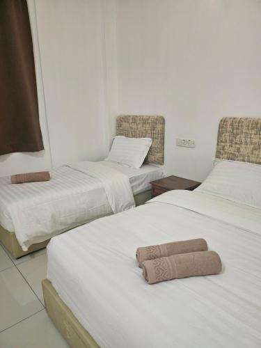 two beds with towels on them in a room at Asia Hotel by AeCOTEL in Sandakan