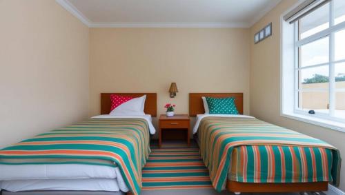 two beds in a room with two windows at Surya Guest House in Kanigaran