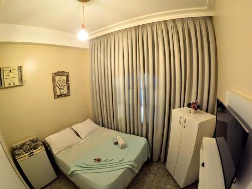 a small room with a bed and a window at Hostel Paraíso in Arraial do Cabo