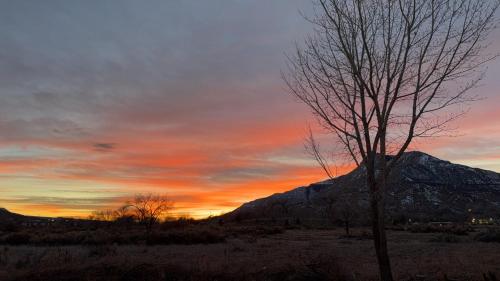a sunset with a tree and a mountain at Western Slope Suites Parachute in Parachute
