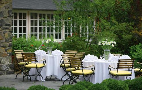 a table and chairs with white tables and flowers on it at Romantik Hotel Jagdhaus Waldidyll in Hartenstein