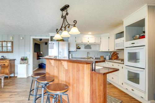 a kitchen with white cabinets and a island with bar stools at Cozy Table Rock Lake Boathouse with Pool Access in Cape Fair