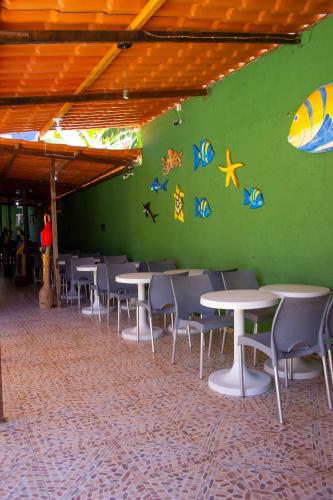 a green wall with tables and chairs in a room at Pousada Mar do Sonho Vila in Porto De Galinhas