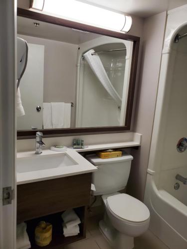 a bathroom with a sink and a toilet and a mirror at Best Western Hotel Brossard in Brossard