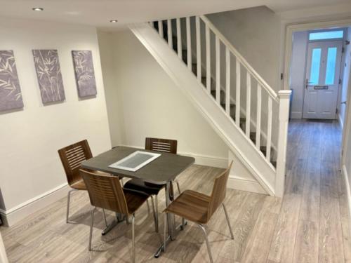 Un comedor con mesa y sillas y una escalera. en Charming 2BR House in the Heart of Colwyn Bay, en Colwyn Bay