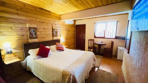 a bedroom with a bed in a wooden room at Pousada Oliveri in Monte Verde