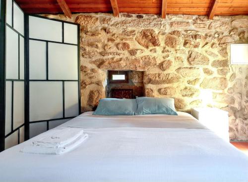 a bed in a room with a stone wall at Cozy studio with mountain view - 20 m² - Águeda in Urgueira
