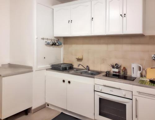 une cuisine blanche avec des armoires blanches et un évier dans l'établissement Appartement lumineux dans le centre de Digne-les-Bains avec balcon., à Digne-Les-Bains