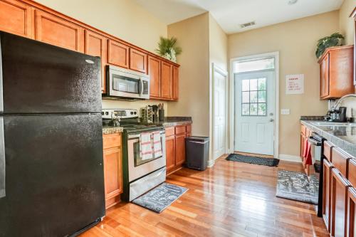 a kitchen with a black refrigerator and wooden cabinets at Free Early Check-In or Late Check-Out - 5 mins to DT & Forsyth - Mini Gym in Savannah