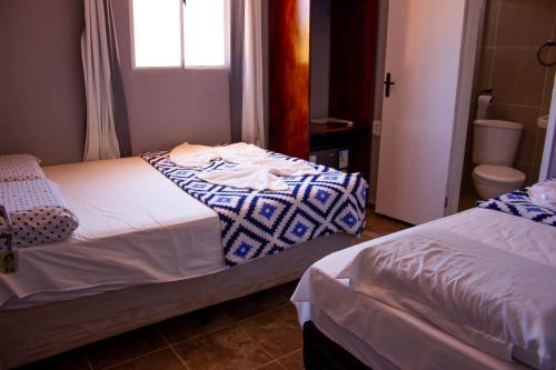 two beds in a small room with a window at Pousada Mar do Sonho Vila in Porto De Galinhas