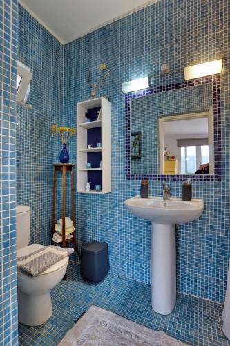 a blue tiled bathroom with a sink and a toilet at Terrace house in Sitia