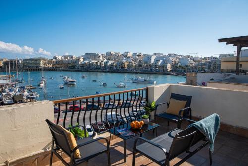 a balcony with chairs and a table with a view of a harbor at Seafront Bedroom with stunning views, balcony and en-suite in Marsaskala