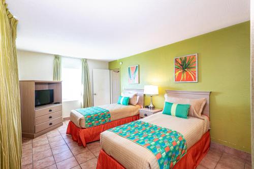 ein Hotelzimmer mit zwei Betten und einem Fernseher in der Unterkunft Enchanted Isle Hollywood Beach Resort in Hollywood