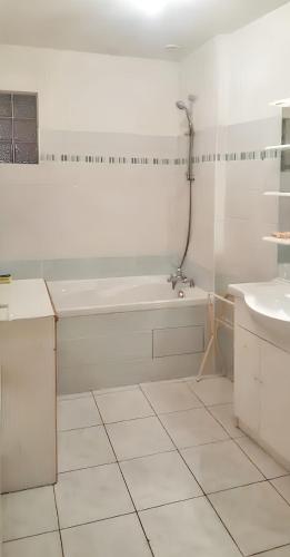 une salle de bain blanche avec une baignoire et un lavabo dans l'établissement Appartement contemporain à Morlaix - 70 m² - proche centre-ville, à Morlaix