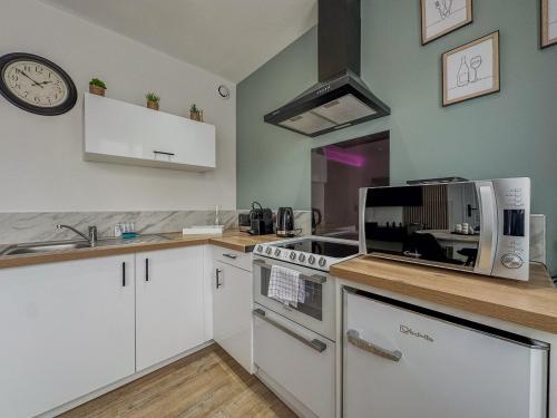 a kitchen with white cabinets and a clock on the wall at MonHac - Modern and comfortable flat in Luisant