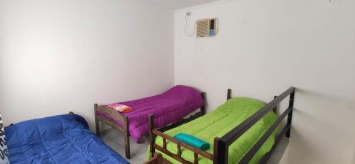two beds in a room with purple and green at Deptos a cuadras del corsodromo in Gualeguay