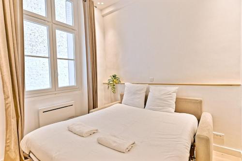 une chambre avec un lit avec des draps blancs et une fenêtre dans l'établissement Studio Chic in Paris- III, à Paris