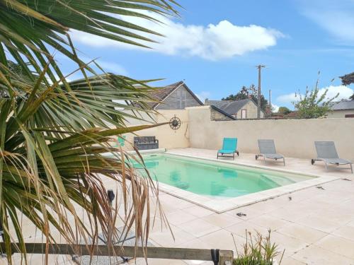 - une piscine avec 2 chaises et un palmier dans l'établissement Maison confortable à Saint-Germain-du-Pert avec piscine privée, à Saint-Germain-du-Pert