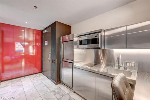 a kitchen with stainless steel appliances and red walls at Stunning Strip View Studio w BALCONY ACCESS 35308 in Las Vegas