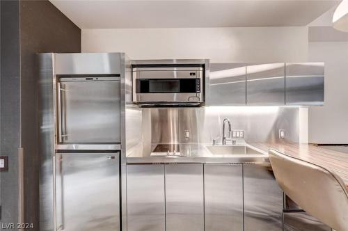 a kitchen with a stainless steel refrigerator and microwave at Stunning Strip View Studio w BALCONY ACCESS 35308 in Las Vegas