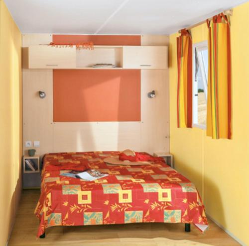 Schlafzimmer mit einem Bett mit einer roten Bettdecke in der Unterkunft Charmant Bungalow à Juncalas avec Terrasse et Vue Montagne in Juncalas