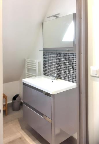 une salle de bain avec un lavabo blanc et un miroir dans l'établissement Maison charmante avec piscine à Loupiac, à Loupiac