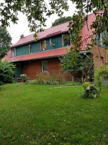a house with a red roof and a green yard at Šilas in Degučiai