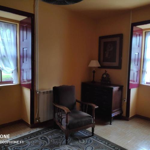 a room with a chair and a table and windows at Casas da Quinta da Cancela in Balugães